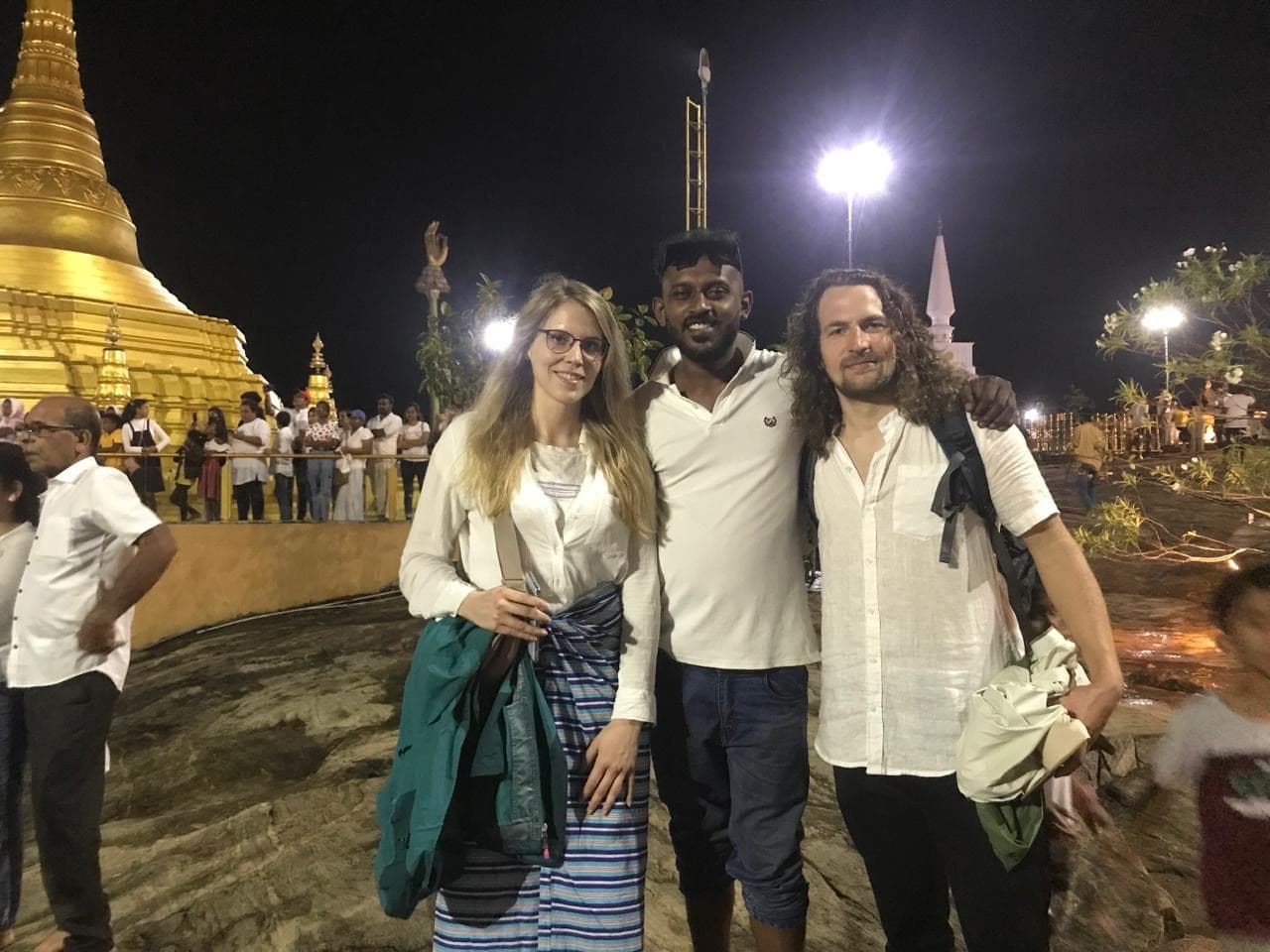Tourists visiting golden Buddhist temple at night in Kandy - cultural tuk tuk tour Sri Lanka